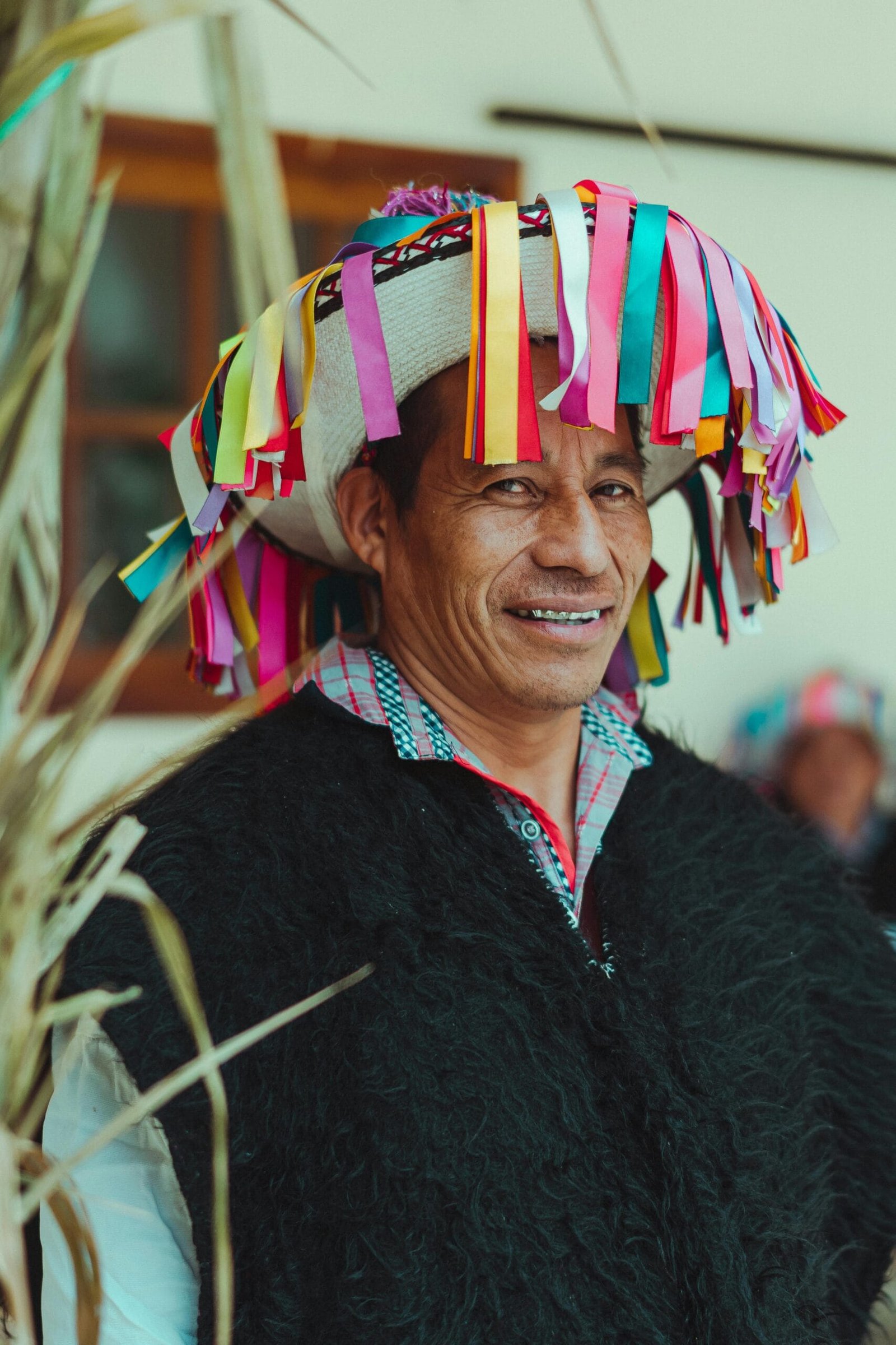 Persona indígena tzotzil con vestimenta típica de San Juan Chamula vestido con piel de oveja color negro con un sombrero tradicional de la región con listones de colores y bordados de color negro y rojo