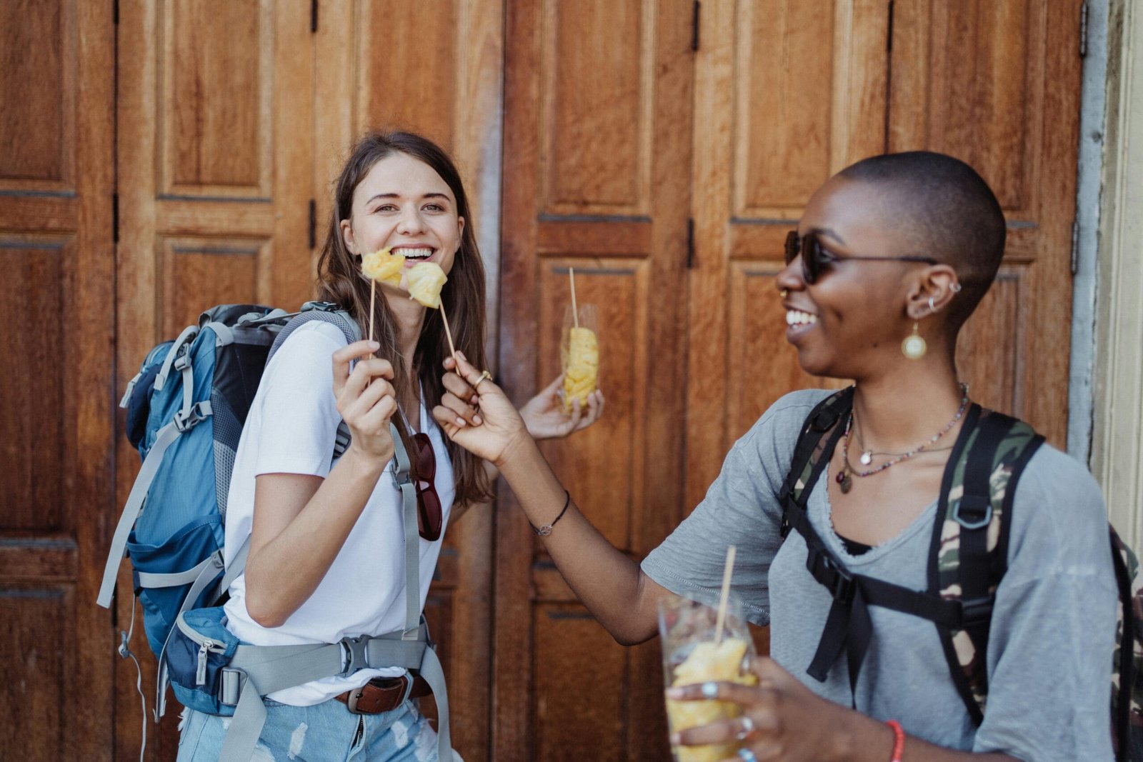 Turistas mochileras a las afueras de un restaurante disfrutando de un postre durante un viaje.
