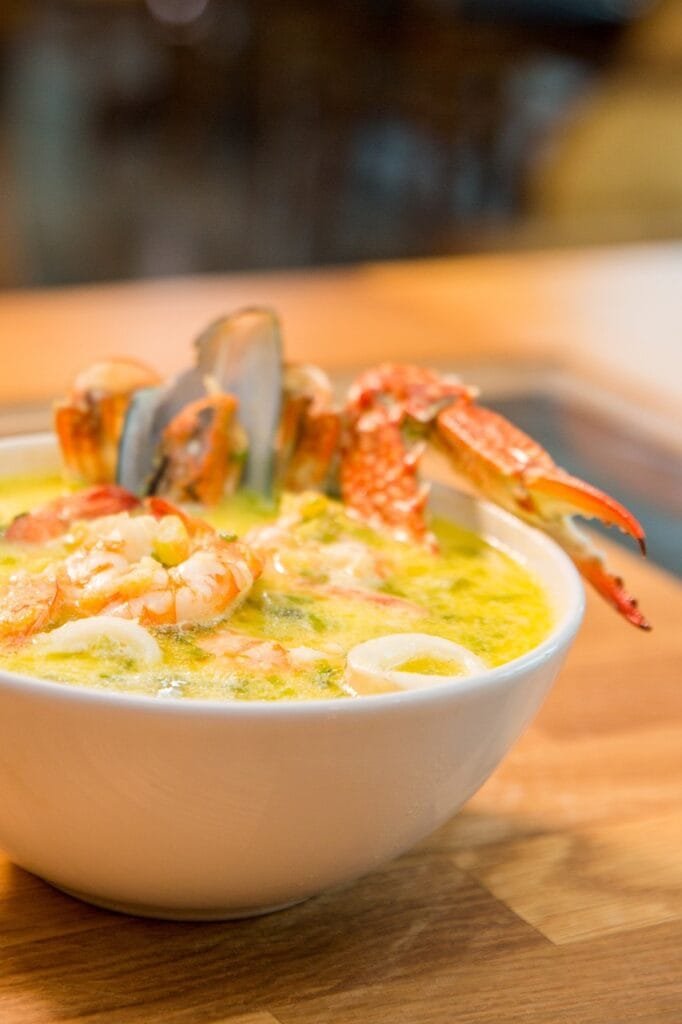Plato de mariscos con caldo de camarones y cangrejo encima de una mesa de madera en una marisquería